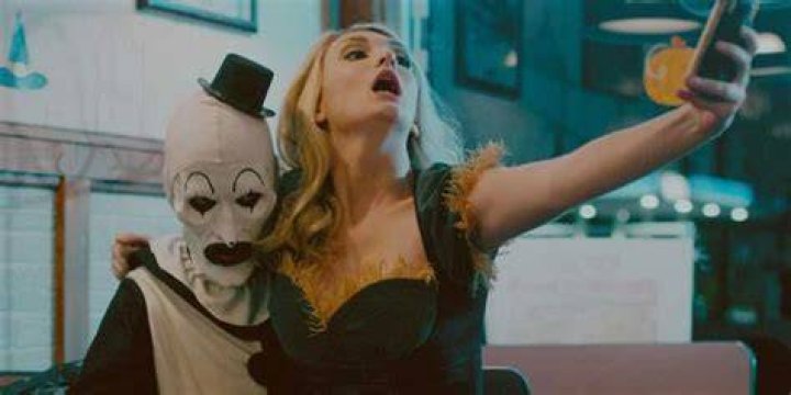Art the Clown and Dawn from Terrifier are taking a selfie in a restaurant.